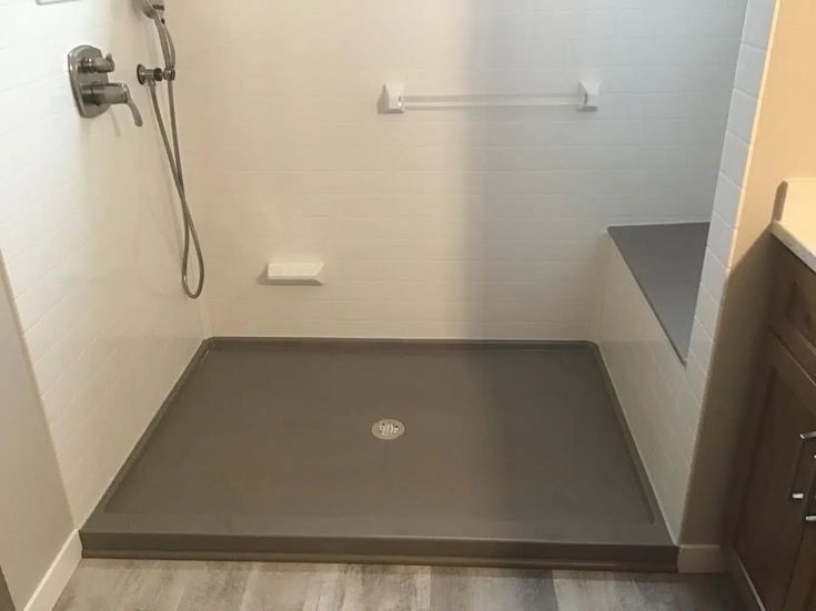 Gray walk-in shower with bench and center drain featuring custom shower base sizes for accessible bathrooms