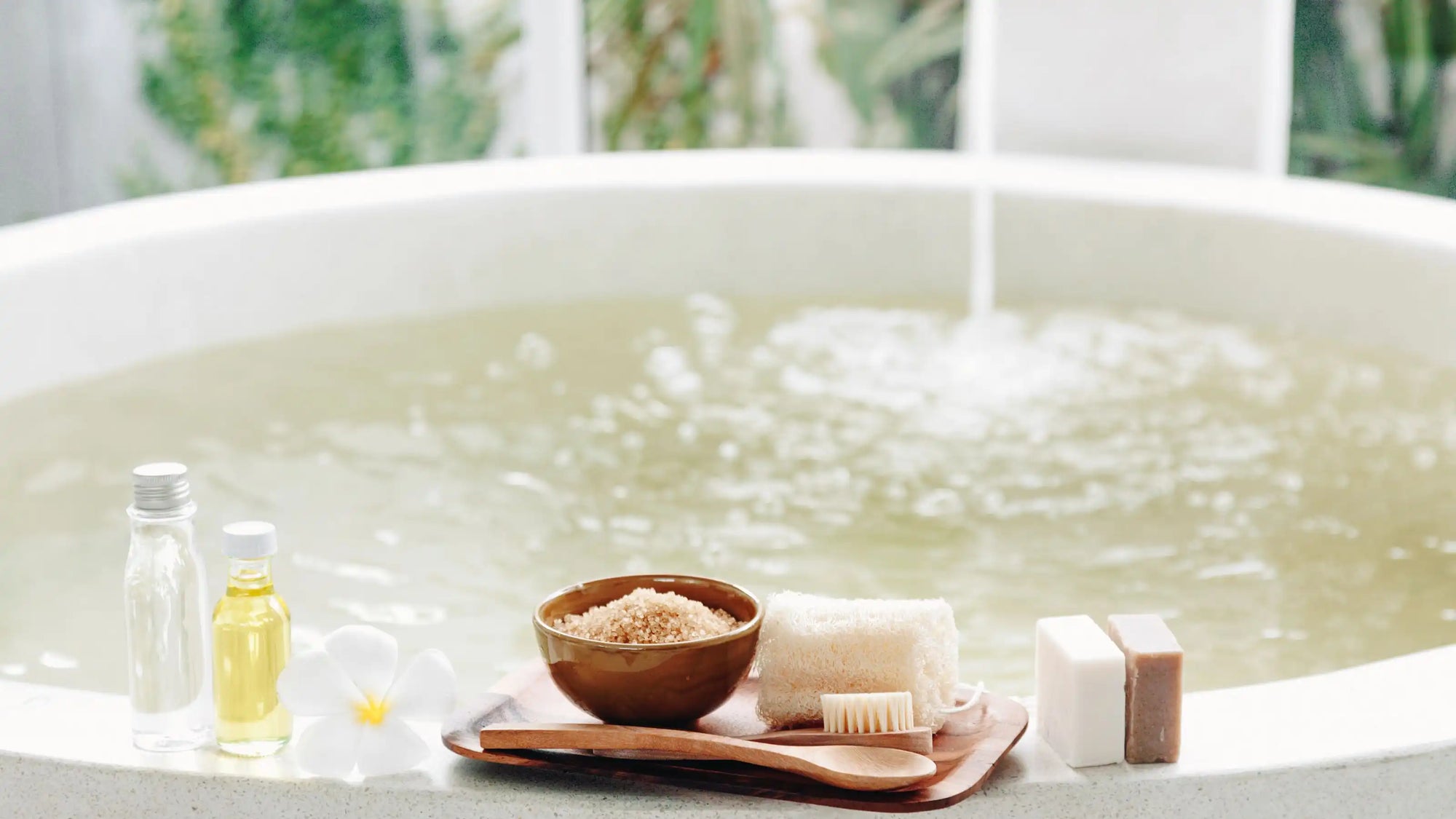 A relaxing spa-style bathtub setup with oils, soaps, and bath tools beside gently rippling water, evoking the perfect bath water temperature | ACE DECOR