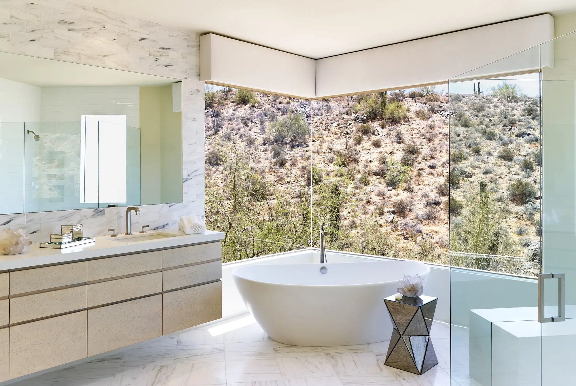 A modern bathroom featuring a freestanding white soaking tub with floor-to-ceiling desert views, showcasing elegant bathtub materials and minimalist design. | ACE DECOR