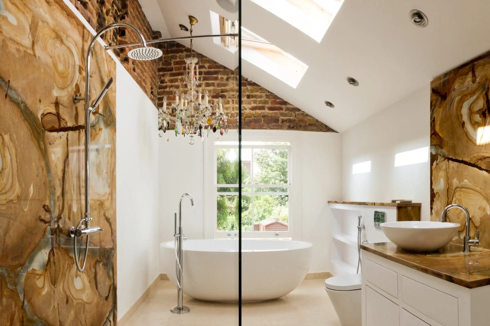 Bright bathroom with freestanding soaking tub under skylights and marble accents | soaking tub dimensions | Ace Decor