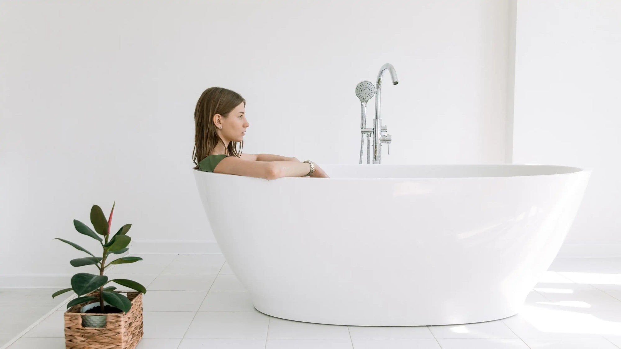 A woman relaxing in a modern white freestanding bathtub, showcasing elegant bathroom design and premium bathtub materials. | ACE DECOR