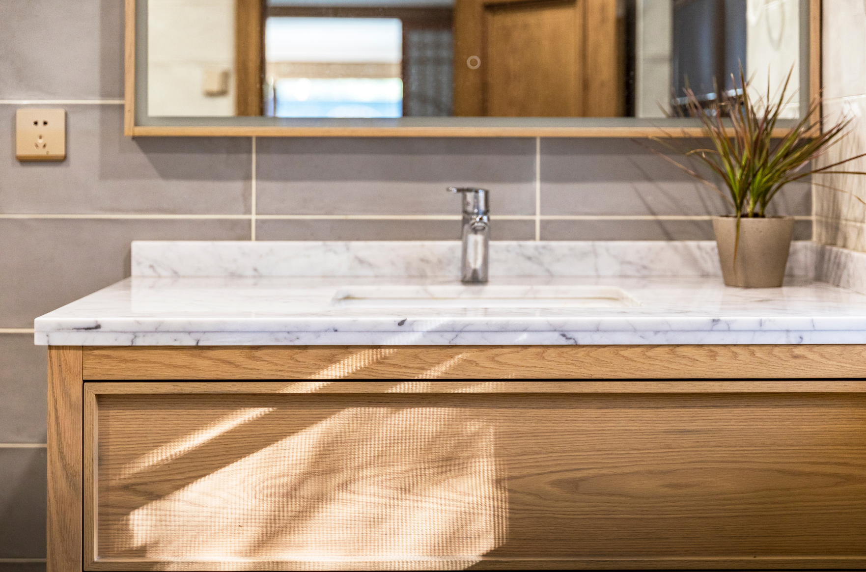 A modern bathroom with a marble countertop and oak cabinets | ACE DECOR