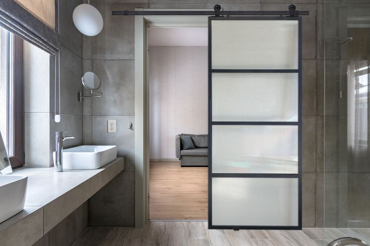 Frosted glass sliding barn door in a modern bathroom setting