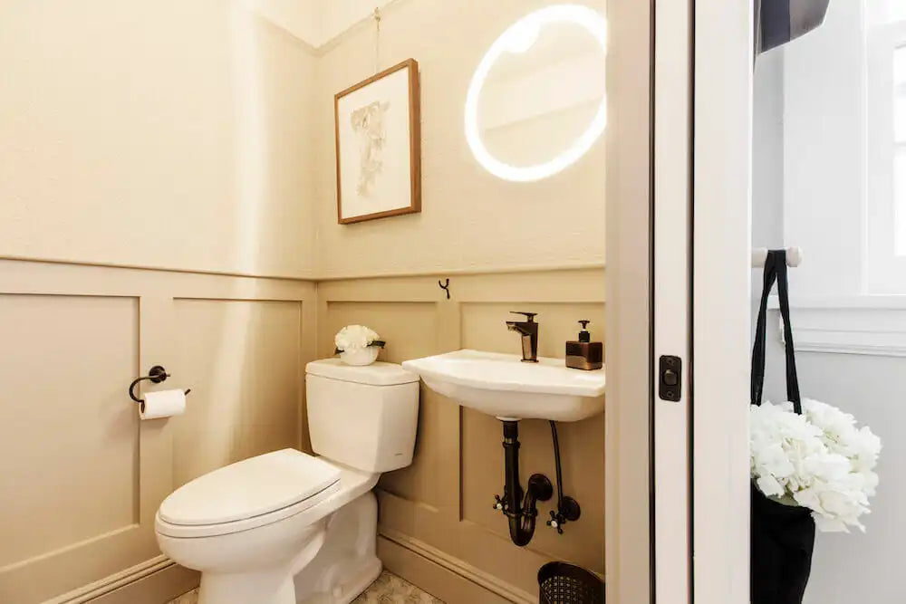Neutral-toned toilet and wall-mounted sink in a cozy corner layout—perfect for very small small half bathroom ideas.