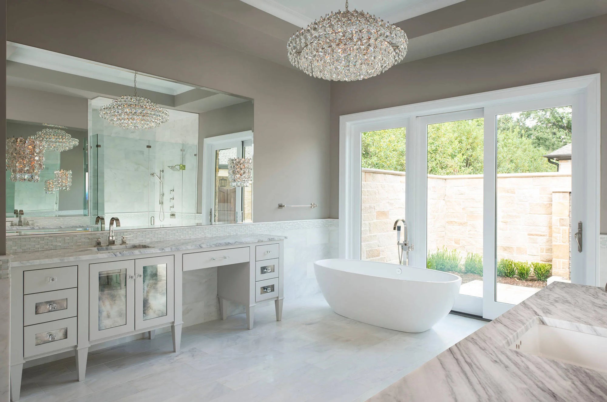 Luxury modern bathroom with large freestanding bathtub near floor-to-ceiling windows showcasing outdoor greenery, double-sink vanity with large mirror