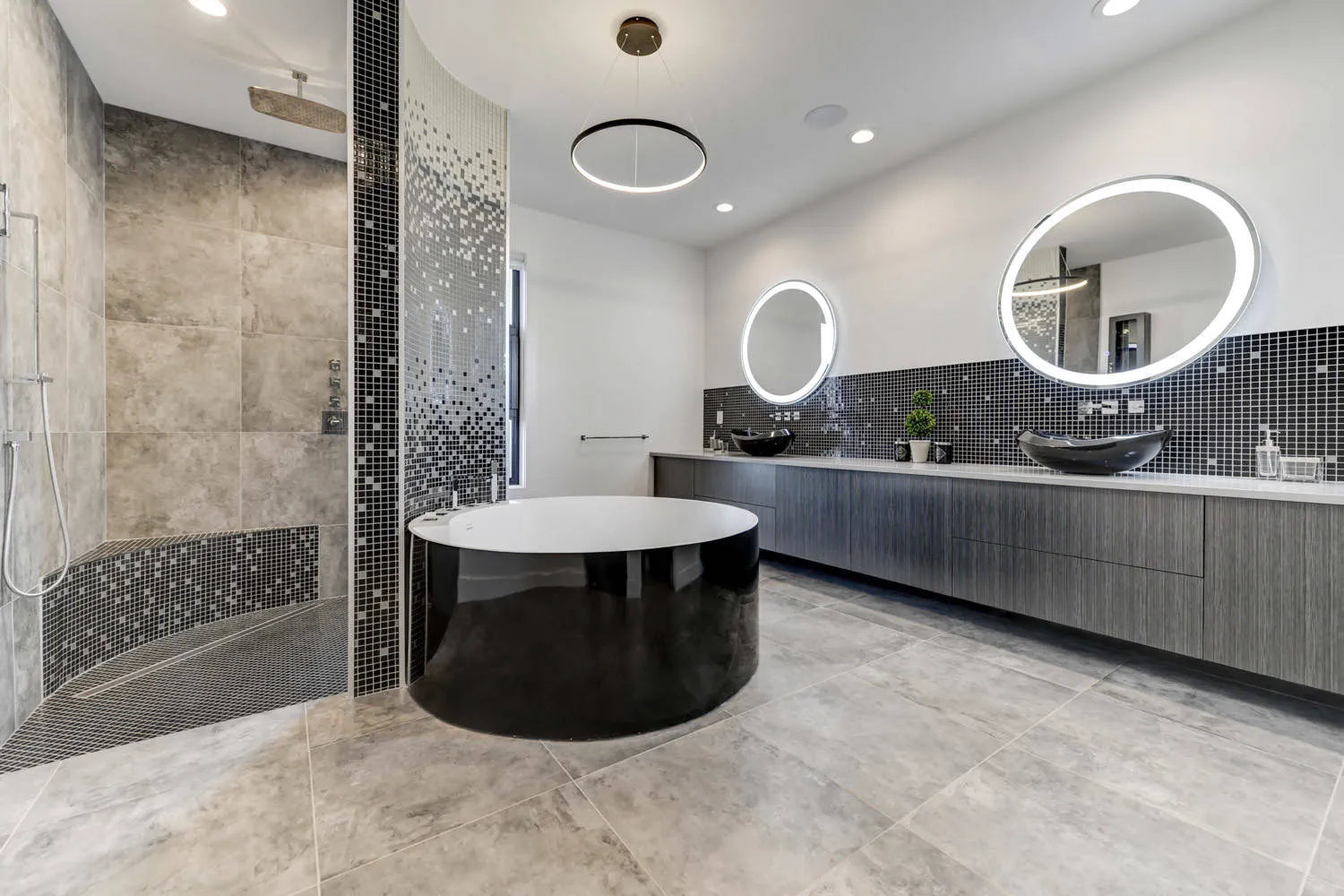 Modern bathroom with black circular bathtub, round mirrored vanity, mosaic tiled shower, and neutral color scheme, sleek contemporary design.