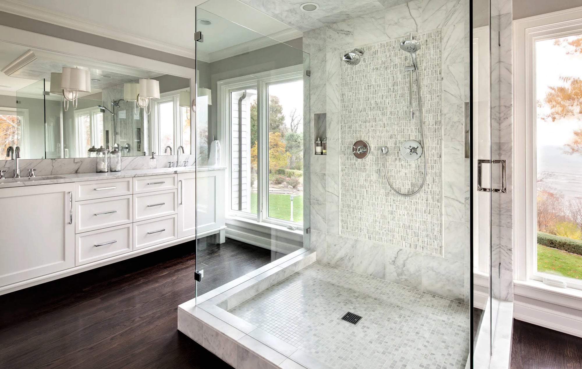 Modern luxury bathroom with a sleek glass-enclosed shower system featuring rainfall showerhead, marble finishes, and elegant design.