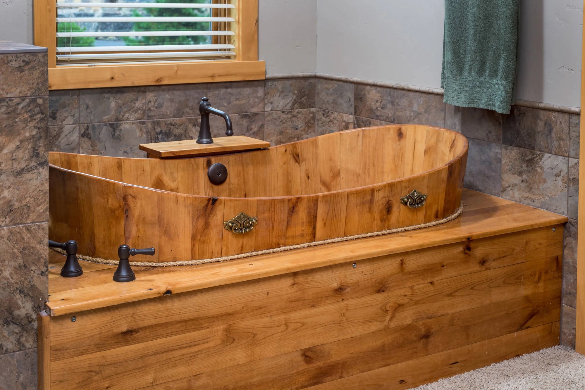 Japanese wooden bathtub with rustic metal fixtures, natural wood grain, and stone walls in serene spa setting.