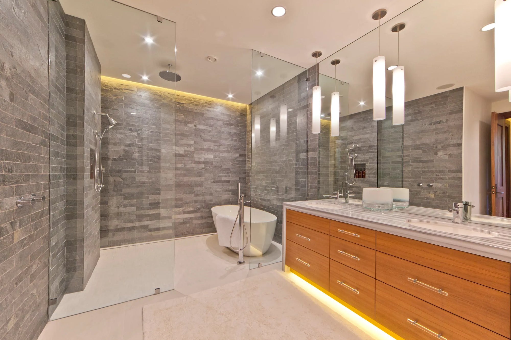 Luxury modern bathroom with gray brick tiles, standalone bathtub, glass-enclosed shower, and double sink vanity featuring bathtubs & shower faucets.