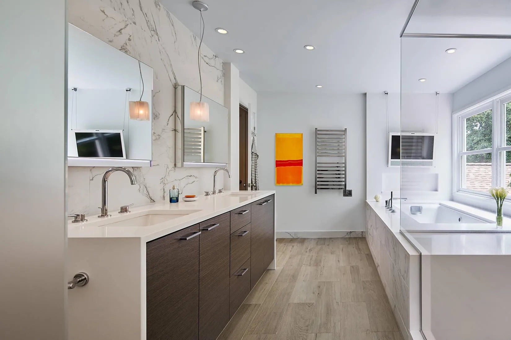 Modern bathroom with double vanities, marble walls, and a heated towel rack for a minimalist, inviting space.