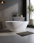 Abyss Series soaking tub in a serene modern bathroom with black freestanding faucet, plants, and natural lighting.