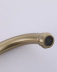 Close-up of VALMIRA brushed gold sink faucet with curved spout and detailed black spray face.