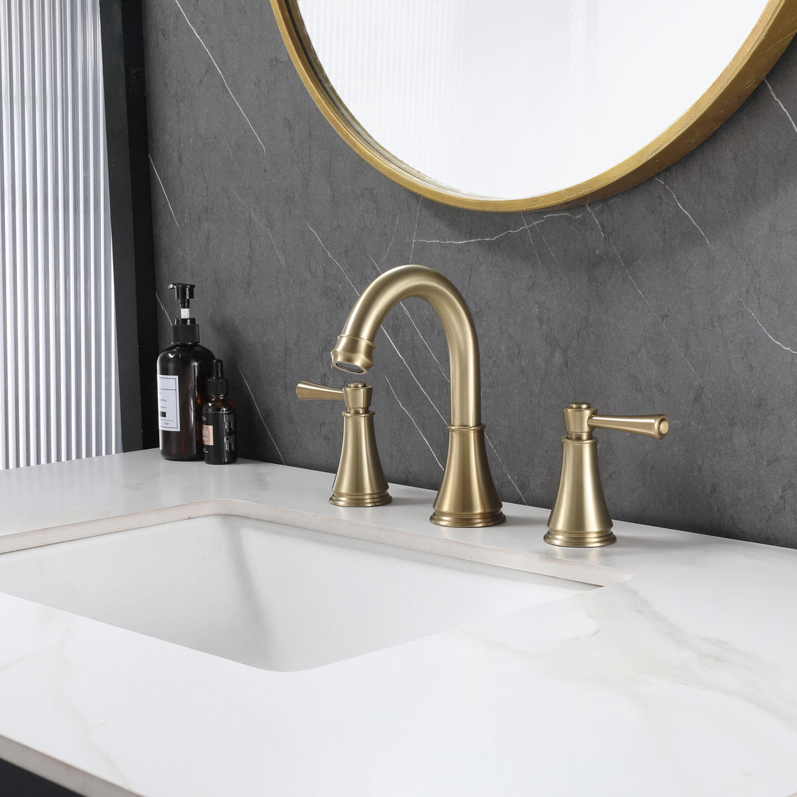 VALMIRA brushed gold sink faucet on white marble countertop with dark gray wall and gold-framed mirror in a modern bathroom setting.