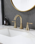 VALMIRA brushed gold sink faucet on white marble countertop with dark gray wall and gold-framed mirror in a modern bathroom setting.