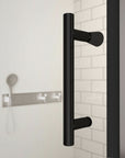 Close-up of Zerra Series matte black shower door handle on clear glass panel.