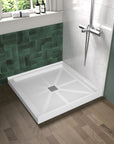 Alcova 36x36 inch square white non-slip shower base installed in a bathroom with green tile and shower system.