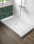 Alcova 60 inch white non-slip SMC shower base with center drain, installed in a modern bathroom with green and white tile walls.