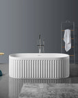 Nectar Series 67-inch solid surface freestanding soaking bathtub in modern bathroom with oval design and vertical ribs.