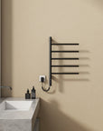 16 x 27 black heated towel rack wall-mounted next to a vanity in a minimalist bathroom | Ace Decor