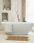 The bathroom presents a sleek stone resin freestanding tub in a minimalist setting with built-in shelves and natural accents. |ACE DECOR