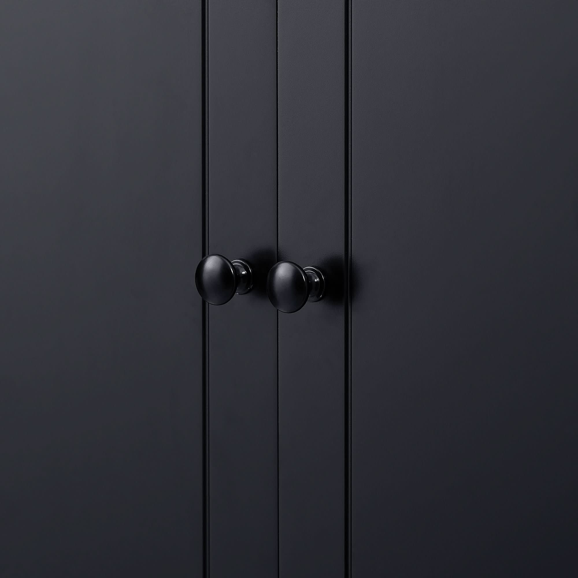 Close-up of matte black round knob on the door of tall storage cabinet.