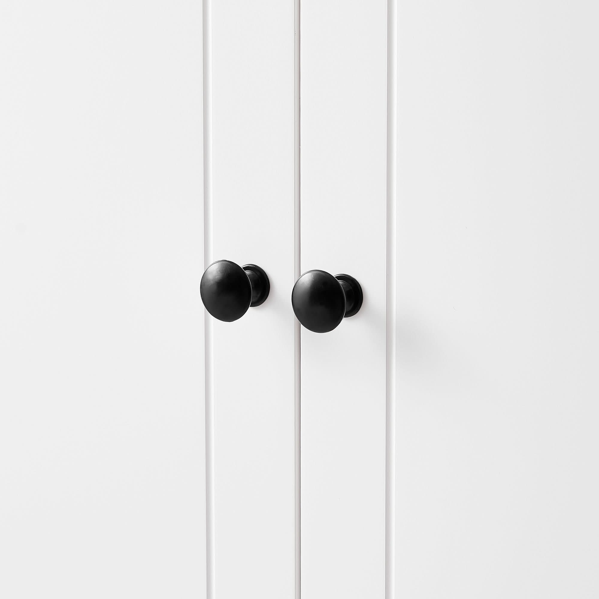 Close-up of round black door knob on white bathroom linen cabinet door.