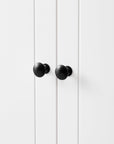 Close-up of round black door knob on white bathroom linen cabinet door.