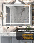 Optera brushed silver LED mirror installed in a modern bathroom with gold accent lighting, marble tile backdrop, and a clear reflection.