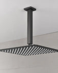 Modern bathroom view showing the Lorton 12" black rain shower head mounted overhead with a wide spray area.