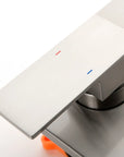 Brushed nickel shower temperature control handle with hot and cold indicators.