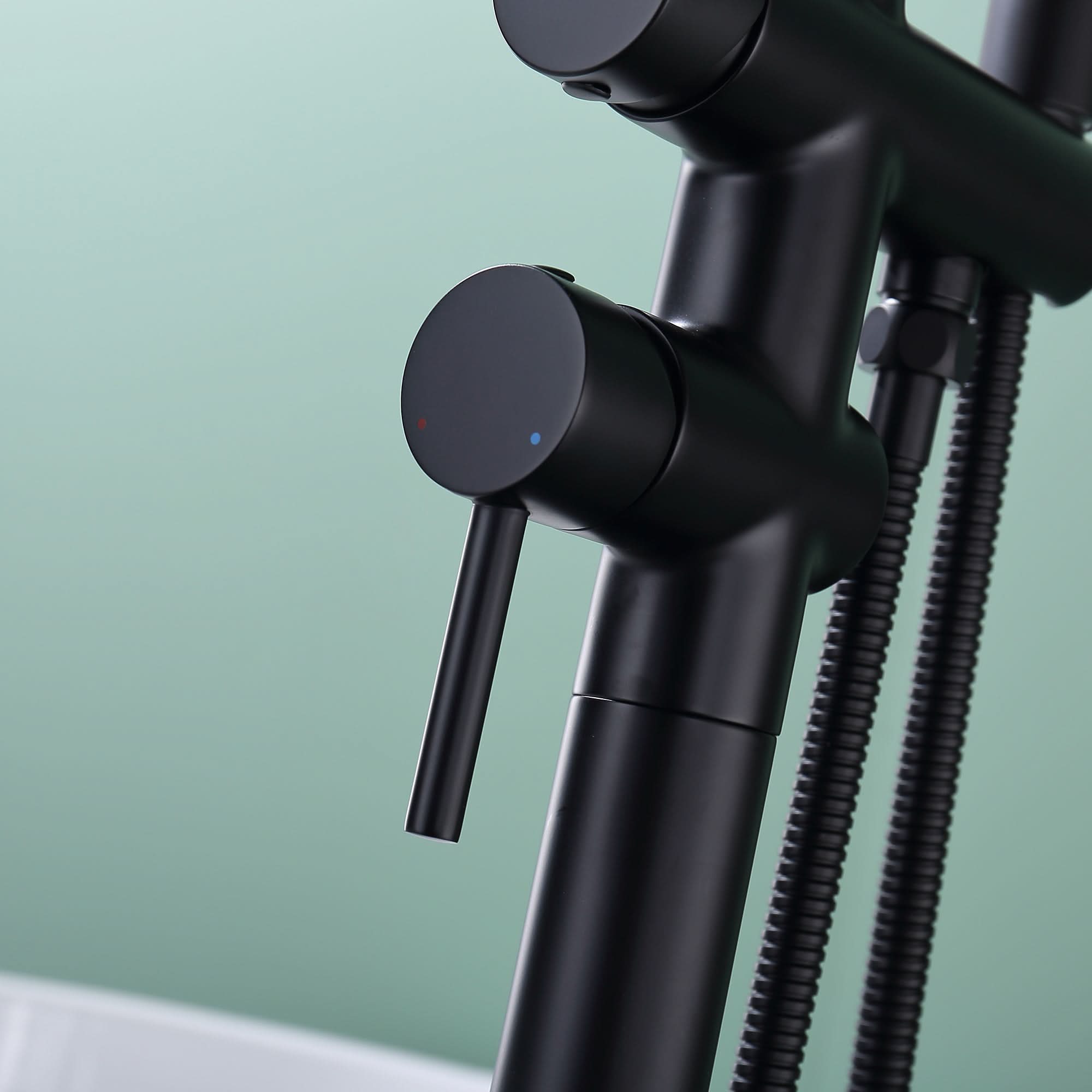 Close-up of handle on Freestanding Black Tub Faucet with Handheld Shower, with hot and cold indicators.