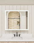 Double-door LED medicine cabinet with lights on above bathroom sink.