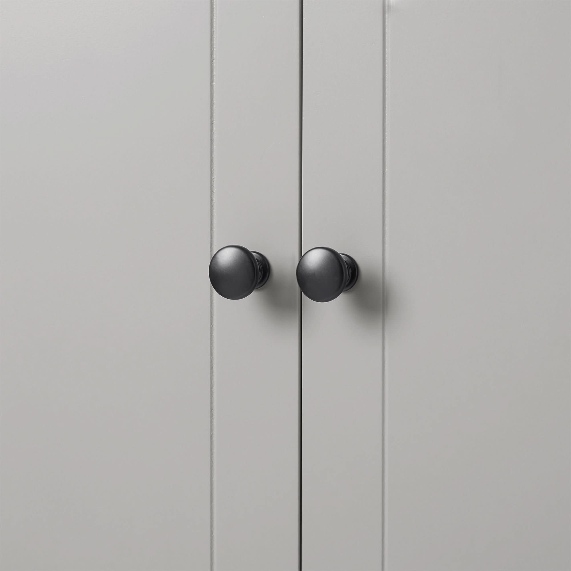 Close-up of round black knob detail on grey linen cabinet door.
