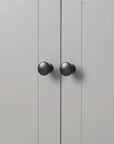 Close-up of round black knob detail on grey linen cabinet door.