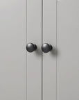 Close-up of round black knob detail on grey linen cabinet door.