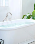 FLUNIX Chrome Waterfall Roman Tub Faucet installed on freestanding bathtub, modern bathroom design with natural light.
