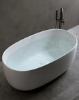 Lissome 47-inch freestanding oval bathtub filled with water in a modern bathroom.