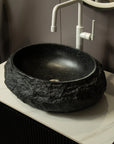Black stone-textured bathroom sink with smooth ceramic inner basin