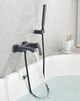 AURELIA matte black wall-mounted bathtub faucet with hand shower installed beside a modern bathtub.