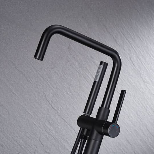 Close-up of Black Freestanding Tub Faucet spout and handheld shower, sleek matte black finish for modern bathroom design.