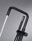 Black freestanding tub faucet spout and handheld shower with spout runing water flow.