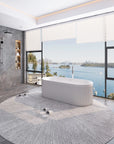 Nectar Series 67-inch solid surface soaking tub in modern bathroom with circular rug, harbor view, and gray marble feature tile.