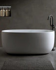 Lissome 47-inch modern freestanding bathtub with black tub faucet in a minimalist grey bathroom setting.