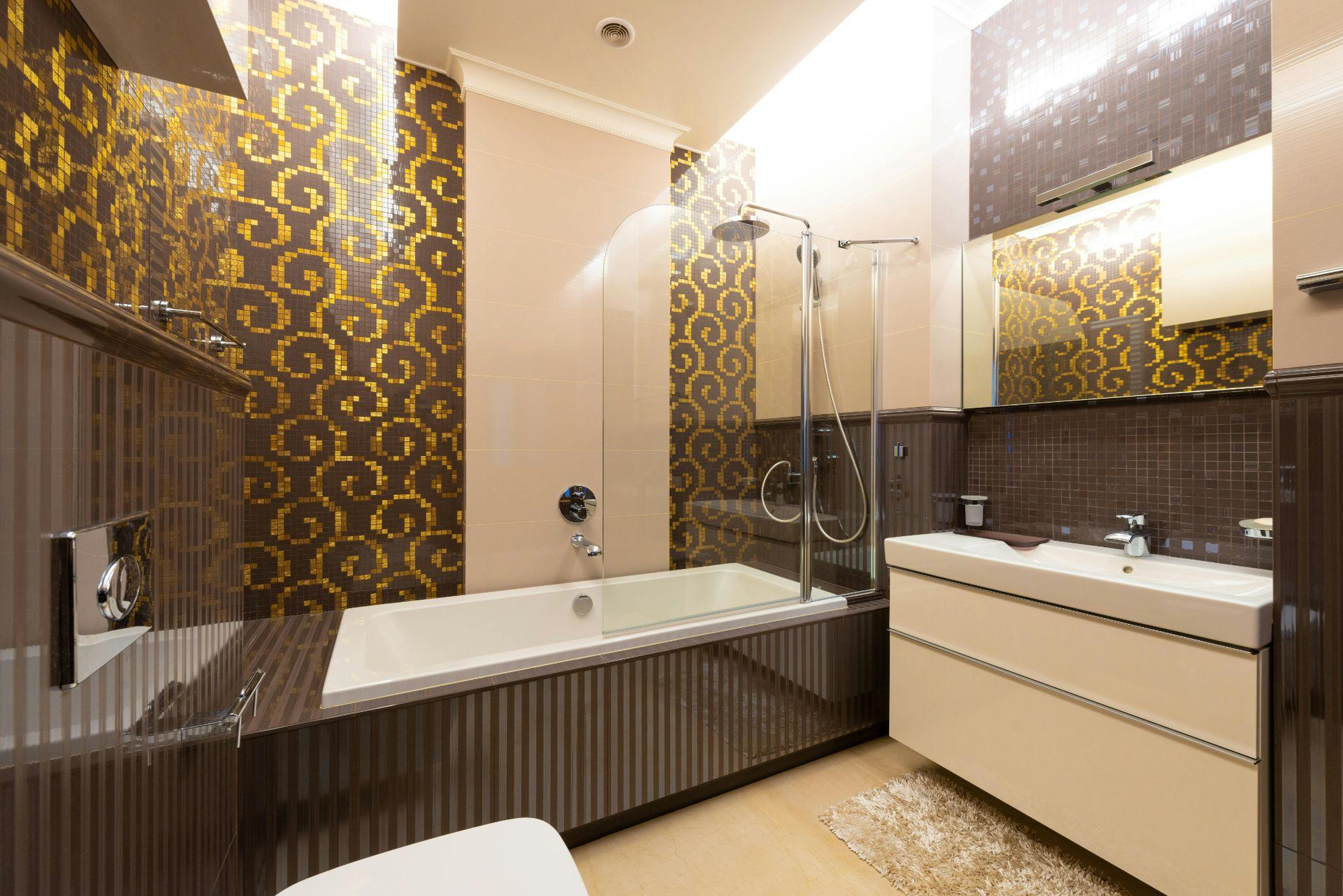 a modern bathroom with bathtub glass doors, featuring a sleek frameless design, stylish gold-accented tiles, and a contemporary vanity setup. | ACE DECOR