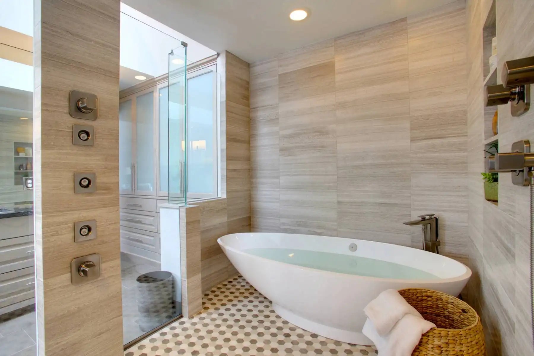 A modern bathroom featuring a deep soaking bathtub filled with water, surrounded by light wood-textured walls and a patterned floor, showcasing ideal bathtub soaking depth for ultimate relaxation. | ACE DECOR