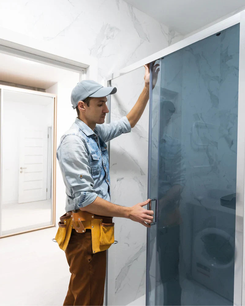 A person is fixing a sliding glass door in a modern room with marble walls.