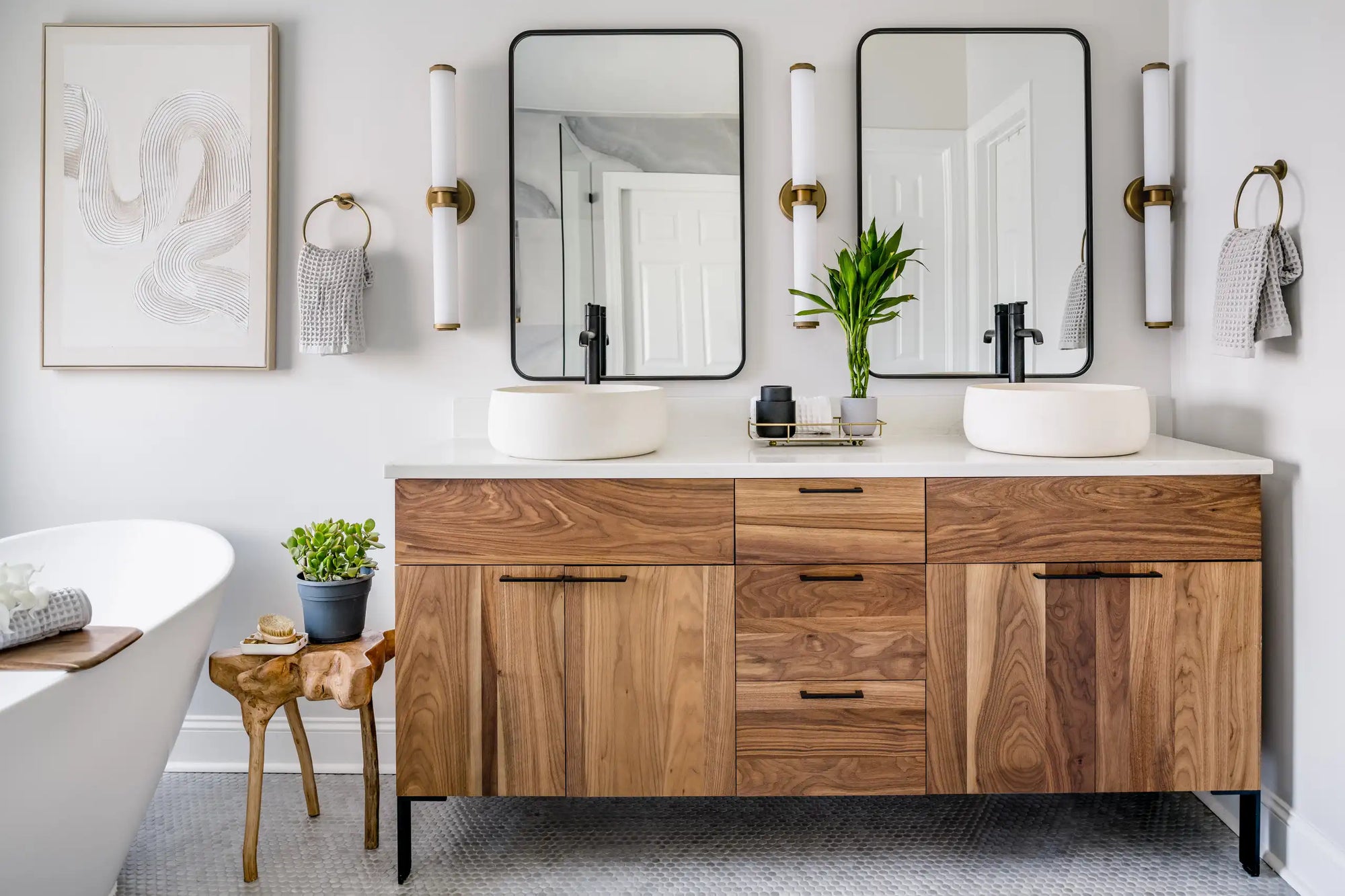 A stylish, modern bathroom featuring a wood-accented freestanding vanity unit with dual vessel sinks and black hardware details. | ACE DECOR