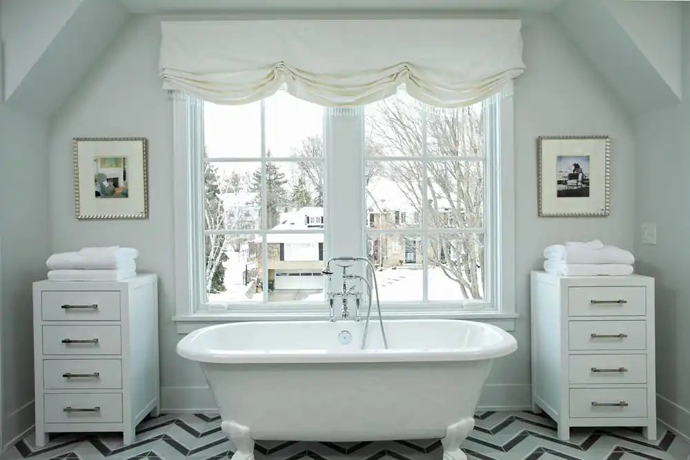 A bright, elegant bathroom features a clawfoot freestanding tub positioned under a large window, showcasing one of the best bathtub styles for luxury and relaxation. | ACE DECOR