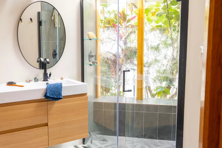 a modern bathroom with a glass shower enclosure, a wooden vanity, and a bright, nature-inspired backdrop. | ACE DECOR