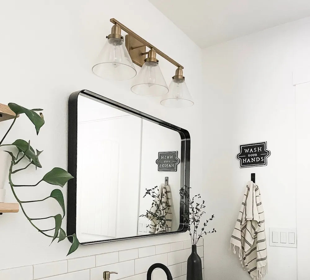 A modern black and white bathroom with a large mirror, wall light sconces above | ACE DECOR